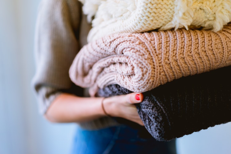 ideje za jesenske fotografije za instagram - djevojka sa savijenim džemperima u rukama